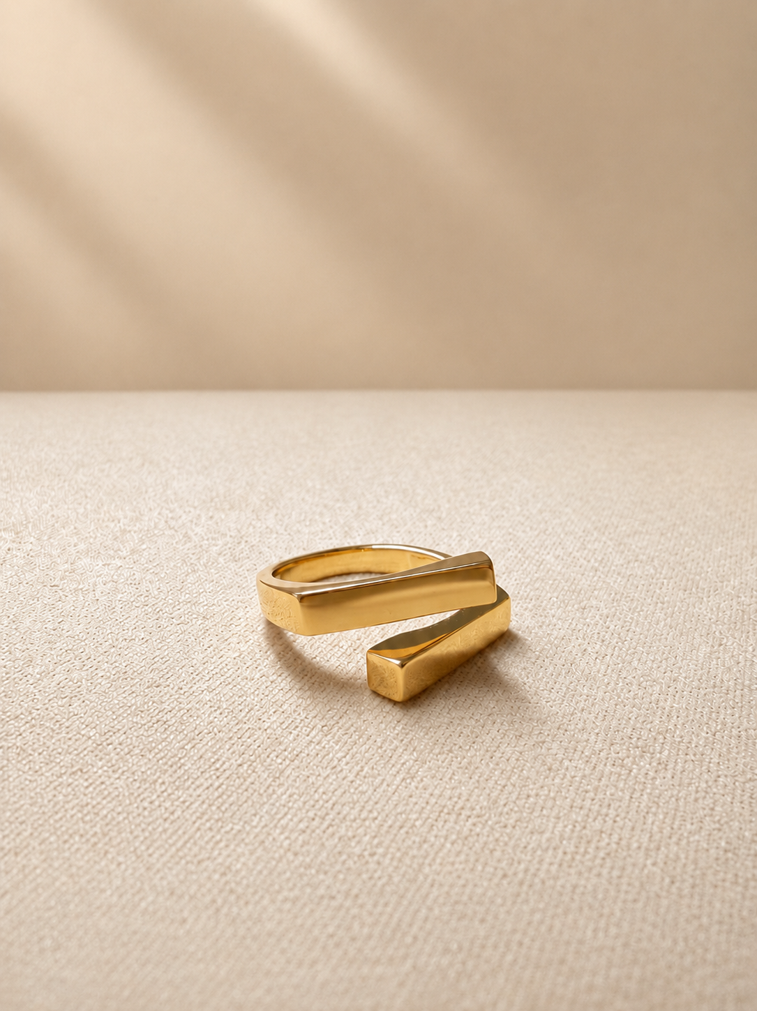 Two square bars cross in a clean geometric silhouette, on gold-plated S925 silver. Open adjustable, minimalist design.