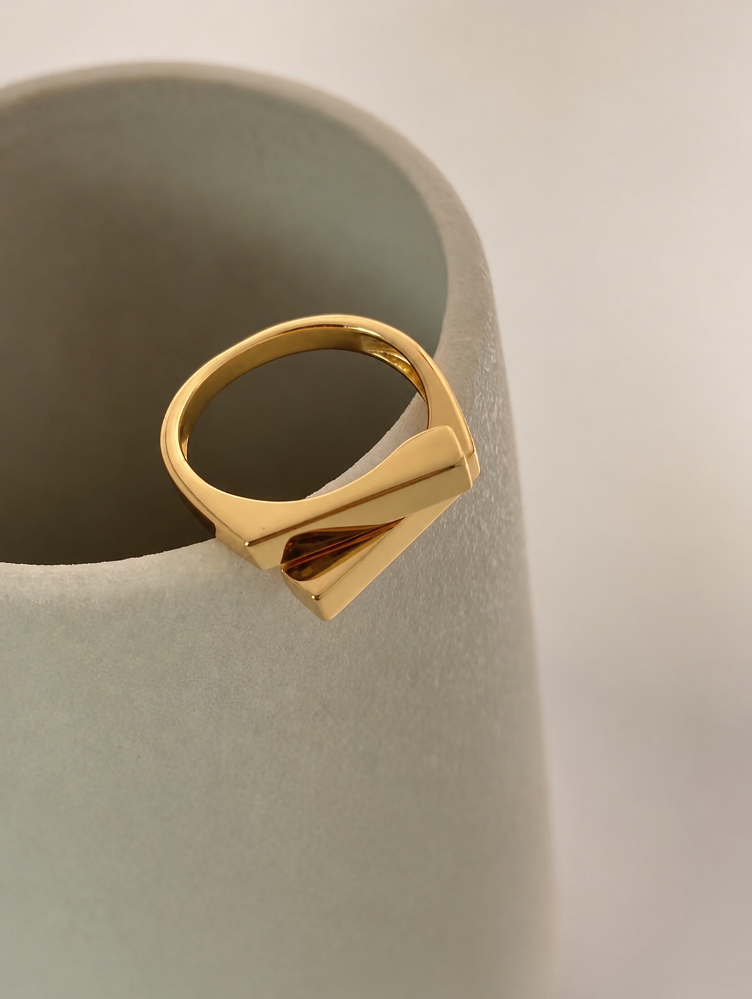 Two square bars cross in a clean geometric silhouette, on gold-plated S925 silver. Open adjustable, minimalist design.