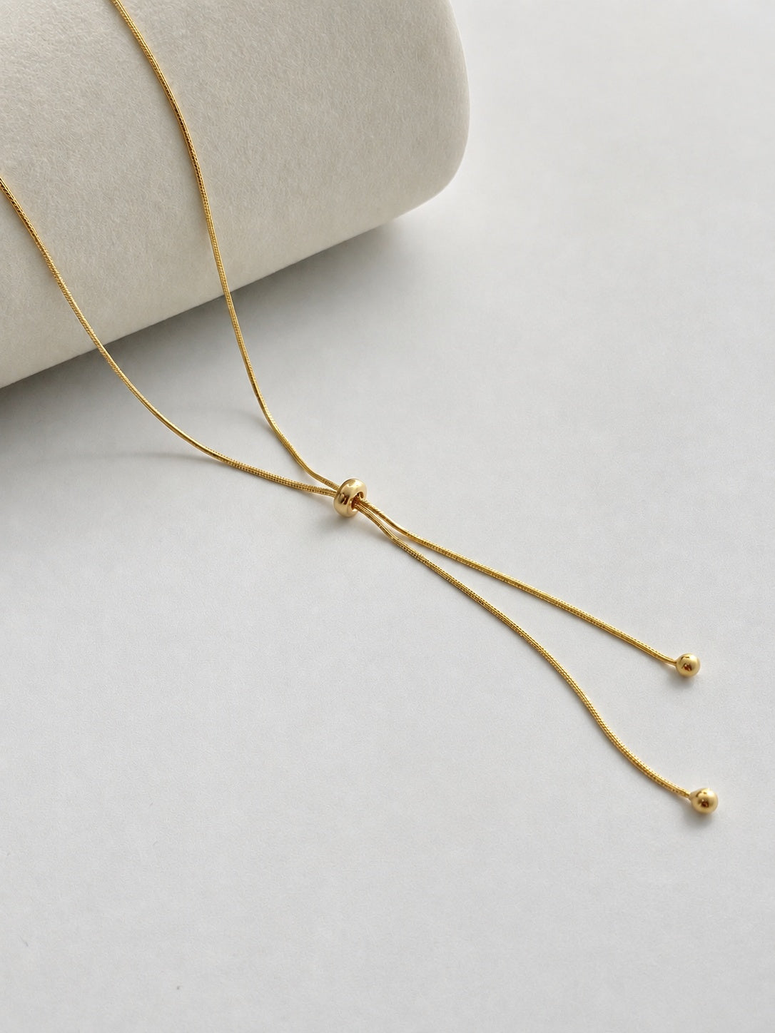 Adjustable snake chain lariat in 18K gold-plated S925 silver. Sliding bead adjuster, dual bead-tipped drops.