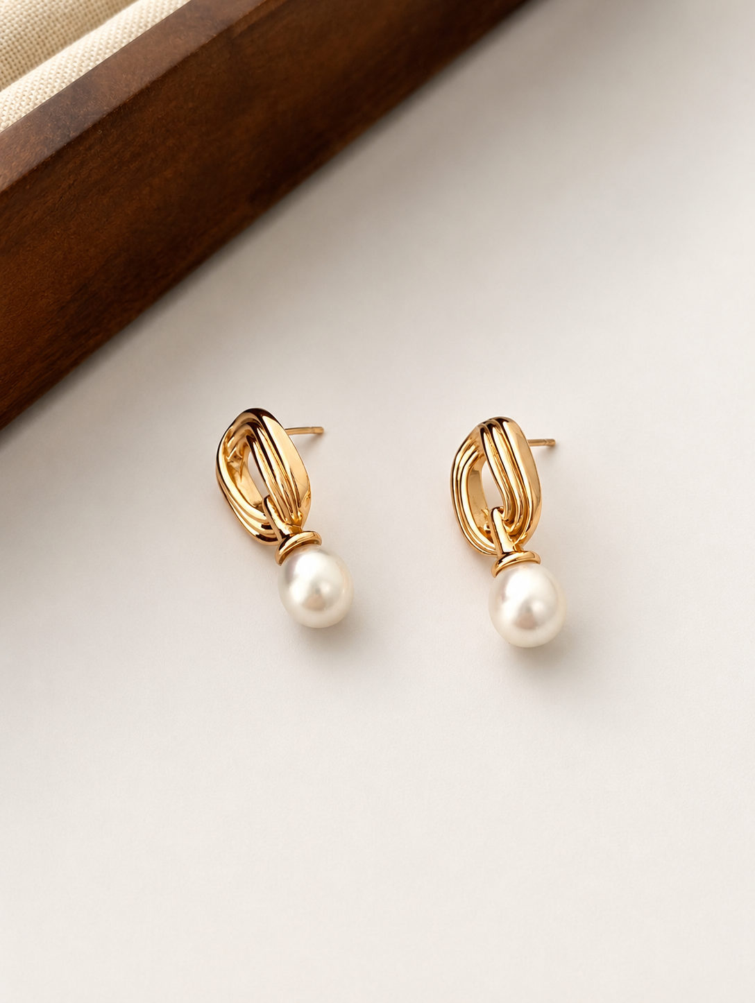 Mobius-inspired gold bands with a freshwater pearl drop, in 18K gold-plated S925 silver. Secure post closure.