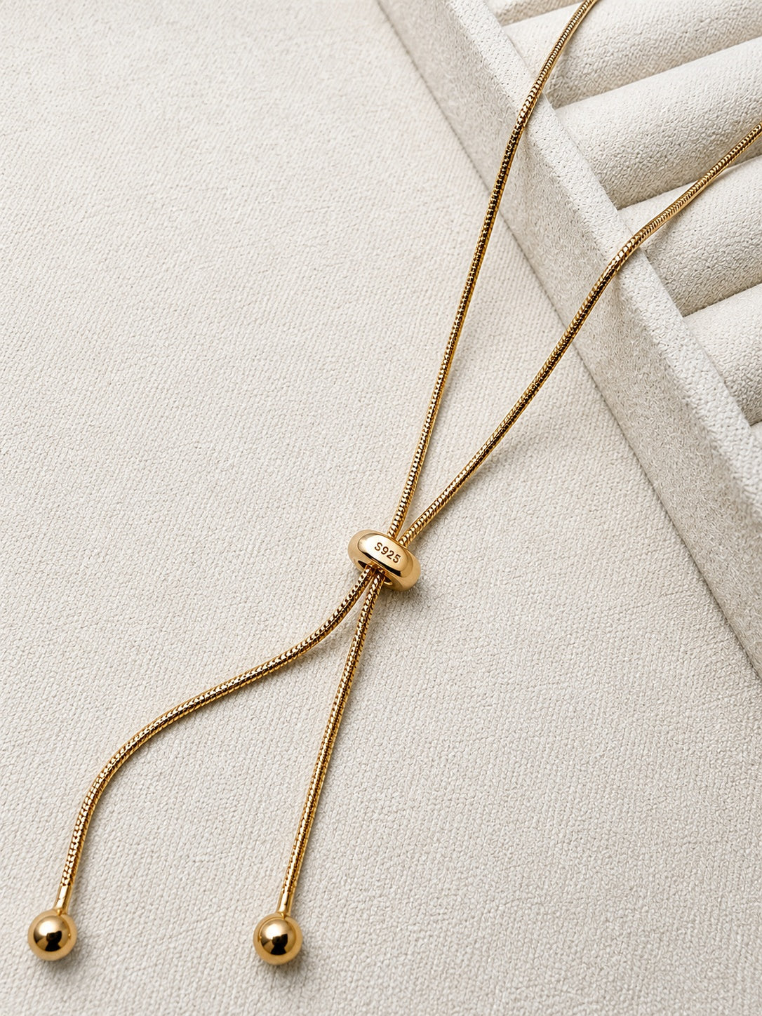 Adjustable snake chain lariat in 18K gold-plated S925 silver. Sliding bead adjuster, dual bead-tipped drops.
