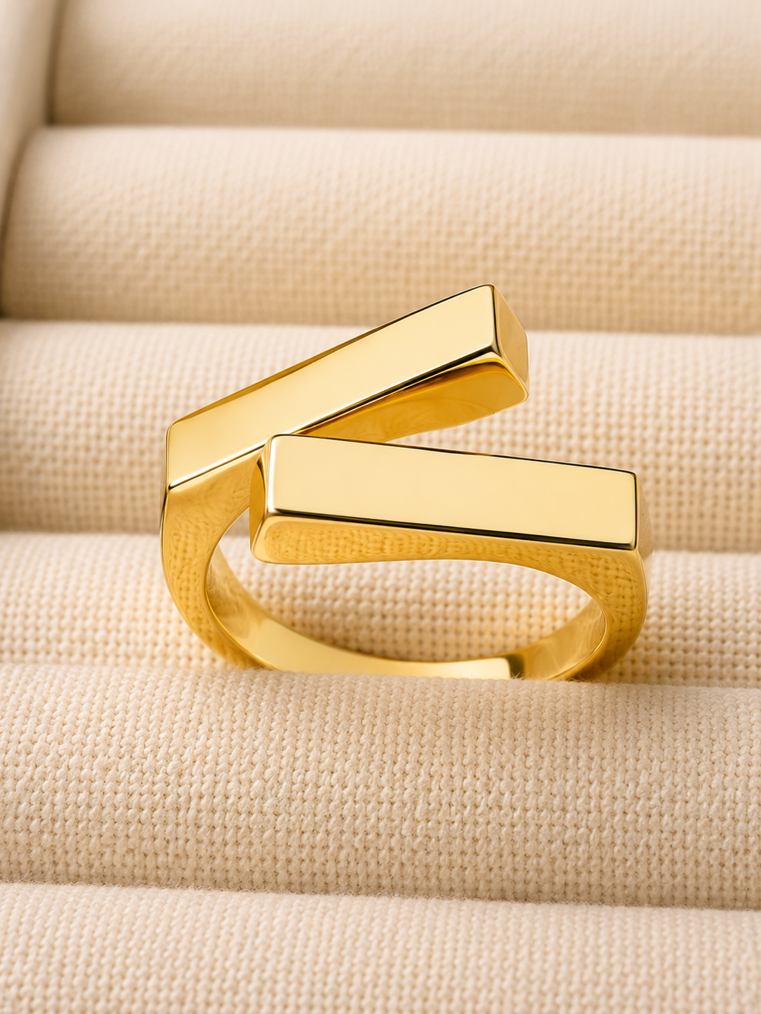 Two square bars cross in a clean geometric silhouette, on gold-plated S925 silver. Open adjustable, minimalist design.