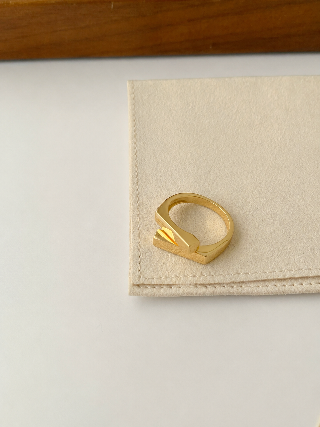 Two square bars cross in a clean geometric silhouette, on gold-plated S925 silver. Open adjustable, minimalist design.