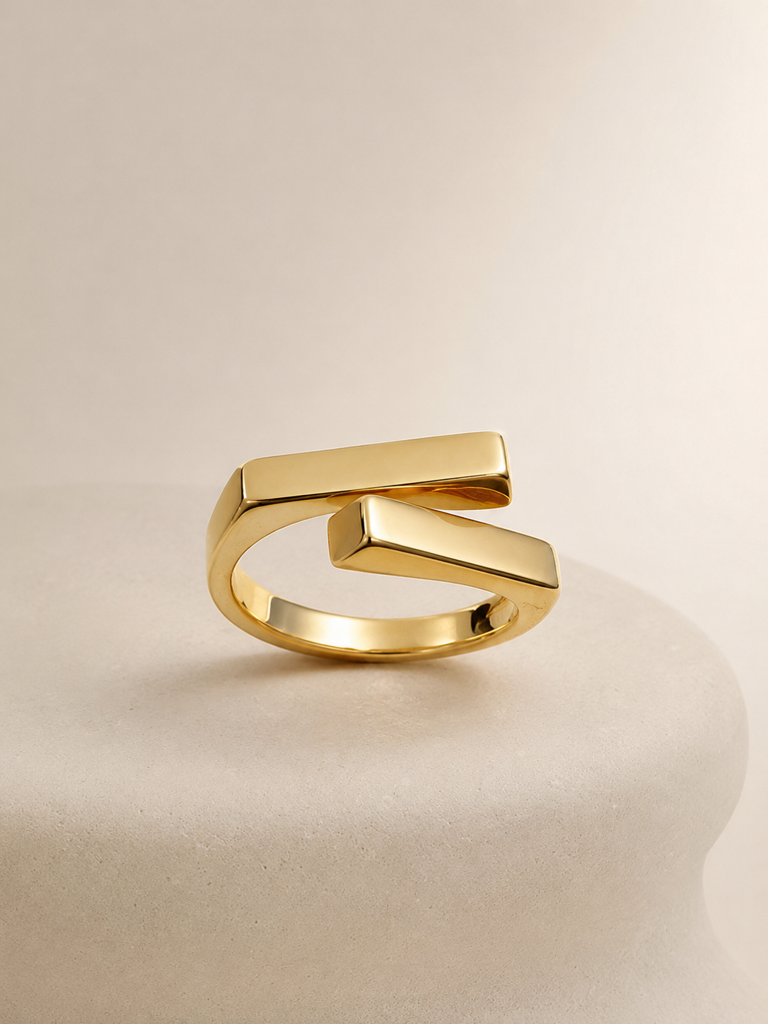 Two square bars cross in a clean geometric silhouette, on gold-plated S925 silver. Open adjustable, minimalist design.
