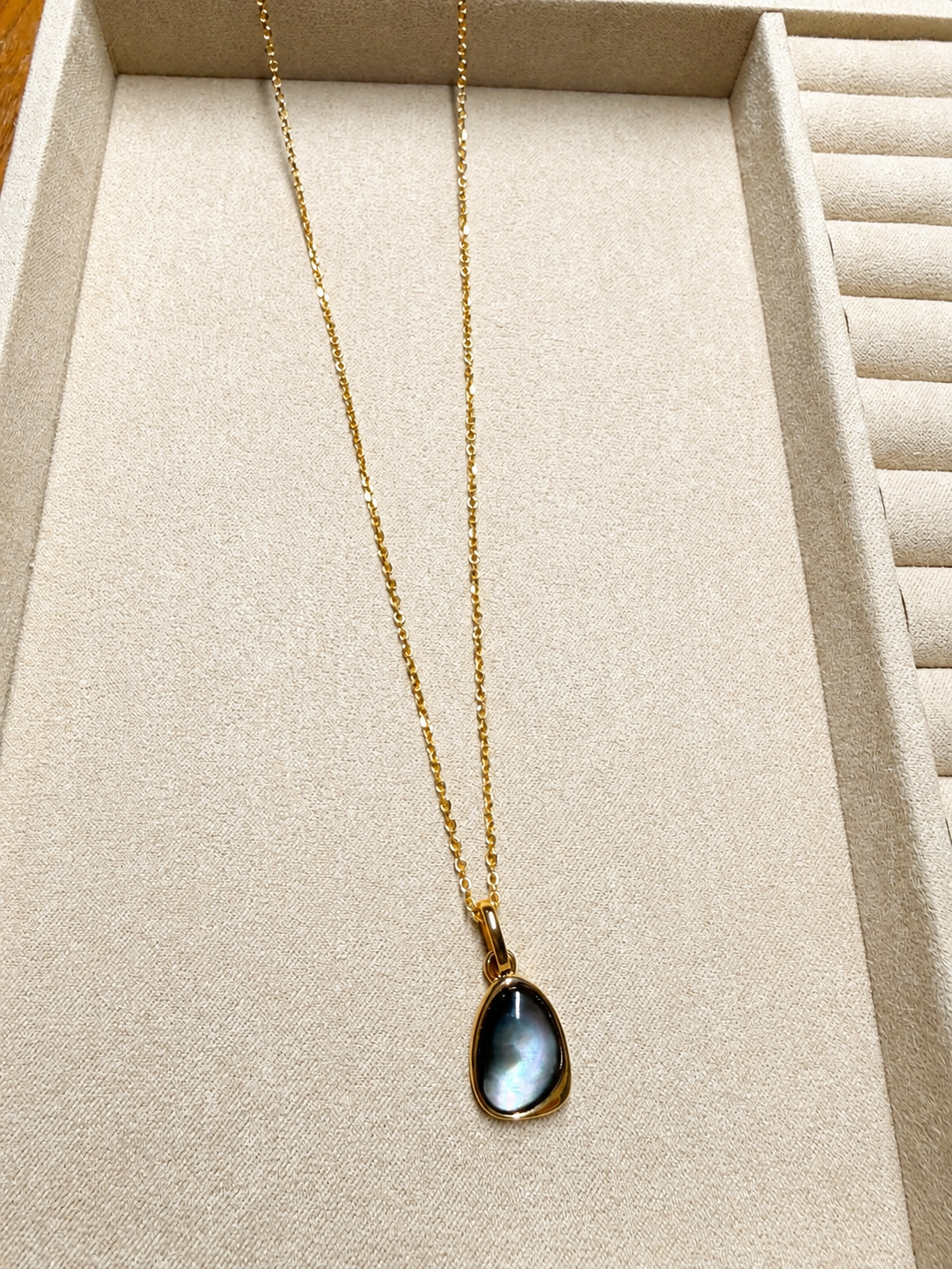Black mother-of-pearl teardrop pendant in gold-plated S925 silver. Iridescent blue-violet tones, 40cm with extender.