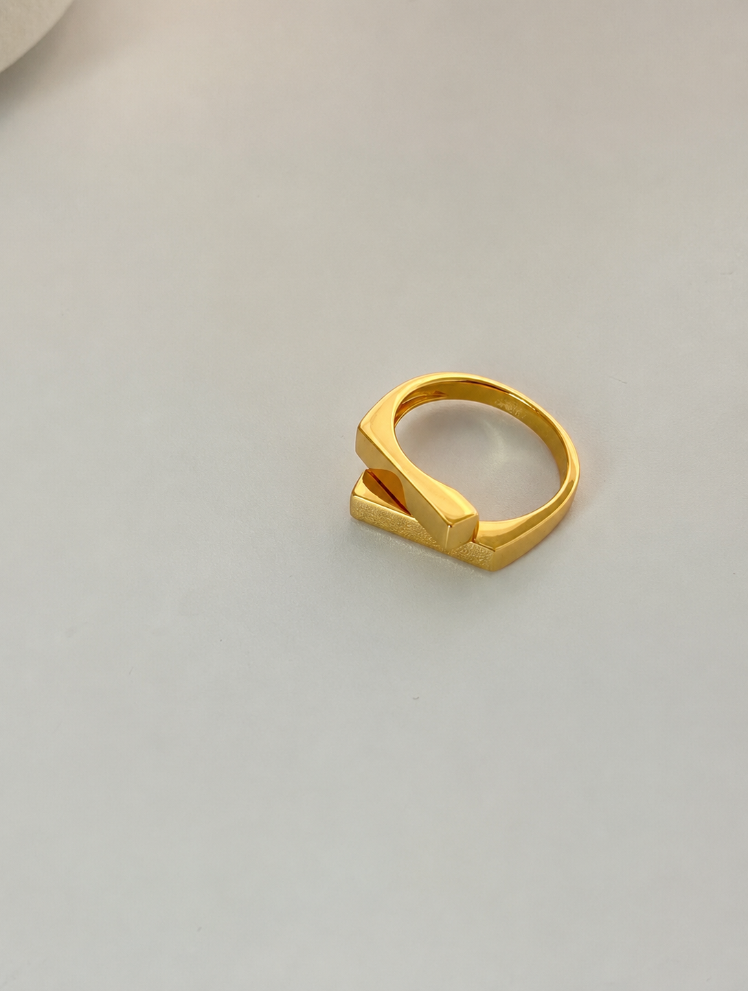 Two square bars cross in a clean geometric silhouette, on gold-plated S925 silver. Open adjustable, minimalist design.